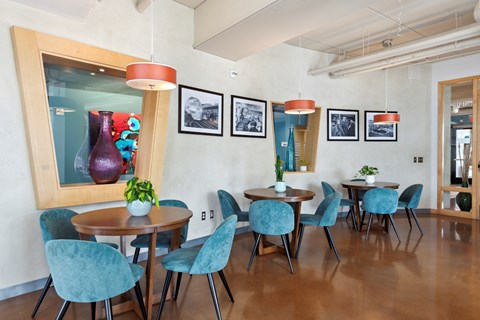 a dining room with blue chairs and a large red vase on the wall